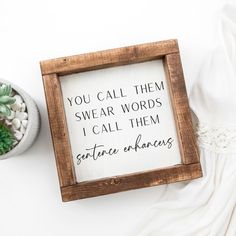 a wooden framed sign with words written on it next to a potted succulent