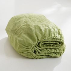 a green blanket folded on top of a white table