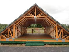 a large wooden structure sitting in the middle of a parking lot next to a field