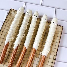 four donuts with icing and sprinkles are lined up on a cooling rack