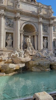 an ornate building with statues on the sides and water running through it's front