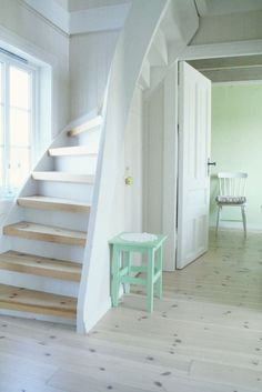 an empty room with white walls and wooden flooring, stairs leading up to the second floor