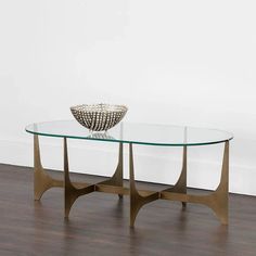 a glass table sitting on top of a hard wood floor next to a white wall