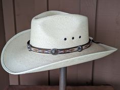 This hitched webbing hatband has a brown leather base that is 15mm wide. Copper patina southwest style Conchos accent the band. Ties on with the deertan lace, slide the deer antler bead bead up to "tighten and tie 2 knots in the lace to secure the band. 23" long. Looks great on both palm and felt hats. Hat not included Traditional Adjustable Hat For Outdoor, Rustic Adjustable Handmade Hat Bands, Adjustable Western Hat Bands For Rodeo, Adjustable Western Hat With Concho, Traditional Adjustable Hat Bands For Rodeo, Western Adjustable Concho Hat, Adjustable Artisan Hat Bands For Ranch, Artisan Adjustable Hat Bands For Outdoor, Southwestern Style Flat Brim Hat Band For Ranch