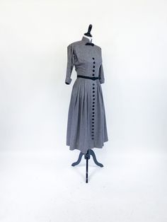 "A fabulously chic vintage day dress from the early 1950s! Medium weight cotton blend in horizontal black, white and gray stripes. Fitted waist and bloused bustline with cuffed ¾ length sleeves cut in one with the bodice. High Nehru collar accented with tailored grosgrain ribbon bow. A-line skirt with gathers at each hip, front and back. Dress closes up the front with a row of 22 buttons that extend from bust to hem. Small shoulder pads and short metal zipper at back neck. Unlined, missing origi 1950s Vintage Dress With Buttons, Retro A-line Dress With Button Closure, 1950s Style Vintage Dress With Button Closure, 1950s Cotton Buttoned Dresses, 1950s Style Knee-length Dress With Button Closure, Grosgrain Ribbon Bows, Afternoon Dress, Halter Maxi Dresses, Crepe Dress