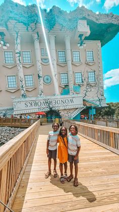 three girls standing on a bridge in front of a building