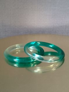 Presented for your consideration is a set of two emerald green and clear bangle bracelets. These bracelets are the perfect way to bring a little "Luck of the Irish" into your world or to add the color green on the festive St. Patrick's Day. The entirety of this set of two emerald green and clear bangle bracelets is in very nice condition.  Dimensions: *Measures approximately 2-5/8" on the inside and 3-3/8" on outside Shipping & Graceful Handling: Item ships via USPS Ground Advantage.   Have a gr Lucite Bangle Bracelet For Gift, Lucite Bangle Bracelet As Gift, Lucite Bangle Bracelets As Gift, Green Plastic Bracelet Jewelry, Green Plastic Jewelry For Gifts, Green Plastic Bracelet, Clear Jewelry, The Color Green, Irish Saints