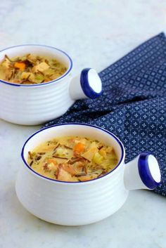 two white bowls filled with soup sitting on top of a table next to a blue napkin