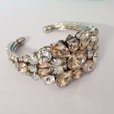 This listing is for the bracelet only Beautiful Bridal Bracelet Art Deco style . Made with clear crystals , white opal, and gold shadow stones set in rhodium plated metal. This bracelet is about 1 1/4 inches wide This is an open bangle so it will fit any wrist size. Matching hair comb at this link: https://www.etsy.com/listing/708567420/gold-shadow-crystal-hair-combwhite-opal?ref=shop_home_active_1 Please contact me if you have any questions. Hand crafted with Love. Glamorous Adjustable Jeweled Bracelets, Glamorous Adjustable Bangle Bracelets, Elegant Cuff Jewelry For Weddings, Elegant Cuff Wedding Jewelry, Adjustable Crystal Cuff Bangle Bracelet, Adjustable Crystal Cuff Bracelet In Bangle Shape, Wedding Jewelry Bangle With Jewels, Formal Crystal Bangle Bracelet With Jewels, Crystal Jeweled Bangle Bracelet For Formal Occasions