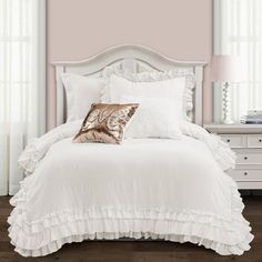 a white bed with ruffled sheets and pillows