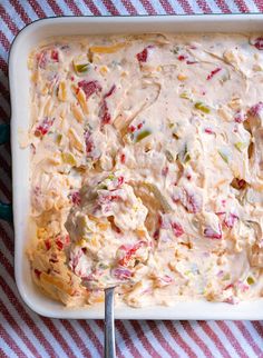 a casserole dish with cheese and vegetables in it on a red and white checkered table cloth