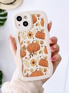 a woman holding up a phone case with pumpkins on it