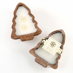 two small wooden boxes with candles inside on a white surface, one is shaped like a christmas tree and the other has a tag