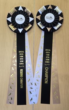 two black and white ribbons with gold foil on them, one is for the competition