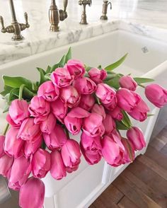 a bunch of pink tulips sitting in front of a sink