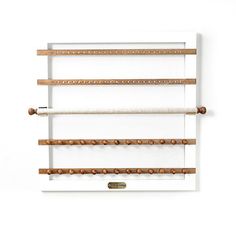 a white wall mounted shelf with three wooden pegs on the top and two different sized pegs below it