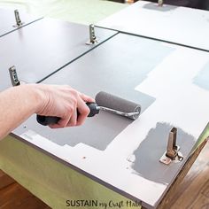 a person using a paint roller to paint a table