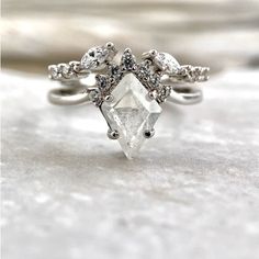 a white diamond ring sitting on top of a piece of silver foil with diamonds around it