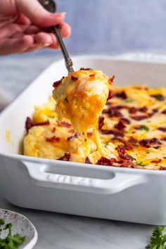 a person scooping some food out of a casserole dish with cheese and bacon