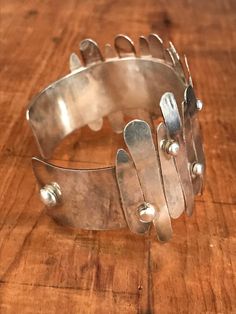 "You will love the way this fabulously unique cuff dresses up your wrist! The inside of this bracelet is a smooth silver band and the outside looks like it's had strips of silver hammered on. This looks like an artisan piece to me. The silver strips are anywhere from 1/2\" to 1 1/2\" long. Please bear in mind that silver is a fairly soft metal, and some of the strips are a bit bent in some areas, but I believe it takes away from the general look of the cuff. Please see all photos for details. I Modern Silver Band Bracelet, Silver Hammered Cuff Bracelet, Silver Hammered Metal Cuff Bracelet, Modern Hammered Metal Cuff Bracelet, Silver Hammered Cuff Bangle, Adjustable Silver Hammered Cuff Bracelet, Contemporary Silver Cuff Bracelets, Modern Silver Hammered Bracelets, Modern Hammered Silver Bracelets