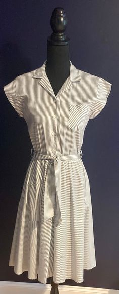 Adorable vintage A-line striped blue and white dress with pockets. Elasticized waist with coordinating fabric belt. V-neck collar with front button closure. Light weight fabric perfect for summer. Excellent condition, pre-washed, clean, ready to wear Measurements: Bust 32" Shoulder to hem 42" Waist 24"-28" Hem sweep 108" Fabric: 50% Poly 50% Cotton Striped Belted Dresses For Daywear, Striped V-neck Shirt Dress For Daywear, Belted Striped Summer Dress, Striped Belted Summer Dress, Summer Workwear Shirt Dress With Striped Collar, Striped Belted Dress For Summer, Classic Summer Dress With Striped Collar, Classic Striped Dresses For Daywear, Striped Short Sleeve Dress With Tie Waist