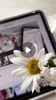 a white flower sitting on top of a tablet computer