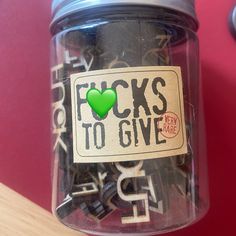 a jar filled with lots of black and white letters on top of a table next to a red wall