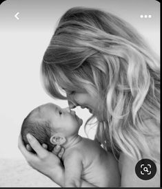 a woman is holding a baby in her lap and kissing it's face with both hands