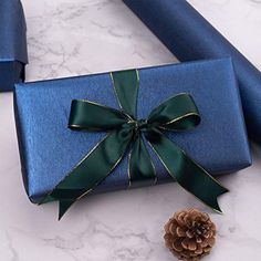 a blue gift box with a green ribbon and a pine cone