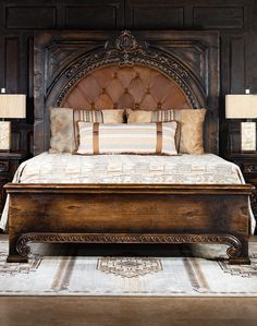 a large wooden bed sitting in a bedroom next to two lamps on either side of the bed