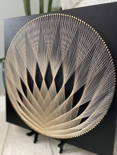 a black and white plate with gold lines on it sitting on a table next to a potted plant