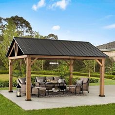 a covered patio with chairs and table in the middle of it, surrounded by grass