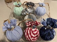 six decorative pumpkins tied with twine and sitting on a counter top, all in different colors