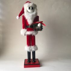 a santa clause figurine holding a christmas wreath on top of a red stand