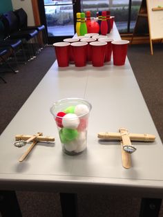 a table topped with cups filled with different colored candies