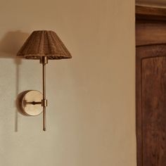 a wall lamp mounted on the side of a white wall next to a wooden door