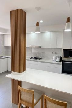 a kitchen with two chairs and a counter in front of a microwave, oven and sink