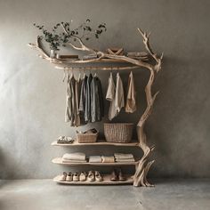 a tree branch shelf with clothes and shoes hanging on the top, next to a shoe rack