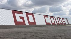 a large red and white sign on the side of a building with clouds in the background