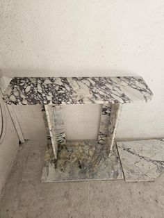 an old marble table in the corner of a room with no one around it,