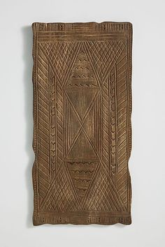 an intricately carved wooden plaque with lines and shapes on it's sides, against a white background