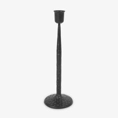 a tall black candle holder on a white background with no one around it or in the photo