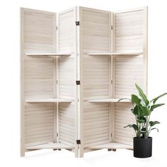 a room divider made out of wooden shutters with a potted plant next to it