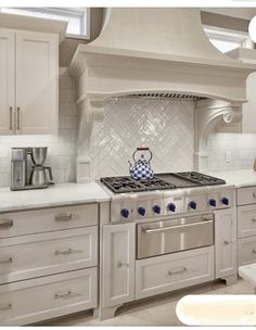 a stove top oven sitting inside of a kitchen next to white cupboards and drawers