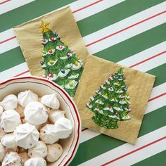 a bowl of marshmallows next to two napkins with christmas trees on them