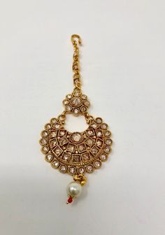 This stunning gold plated colored tikka with stonework is just what you need to add that unique touch to your outfit!  This maang tikka features golden clear stones and gold polish, simple enough to pair with a large variety of sets and earrings for an added elegant touch and is perfect with any hairstyle.  Take your next outfit to extra glam levels with this piece for your night out or special day!  Dimensions -  Width (at widest part) - 1.5 inch  Length (of pendant from top where chain starts Adjustable Gold Kundan Necklace With Stone Work, Traditional Jeweled Tikka For Festive Season, Gold Tikka With Latkans For Festive Occasions, Gold Tikka With Latkans For Celebration, Festive Gold Tikka With Latkans, Gold Kundan Necklace With Stone Work For Festivals, Festive Chandbali Jeweled Tikka, Gold Tikka With Tilla As Gift, Jeweled Temple Jewelry Tikka As Gift