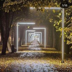 an empty walkway in the middle of a park at night with light painted on it