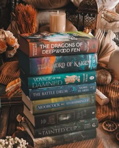 a stack of books sitting on top of a table next to a candle and flowers