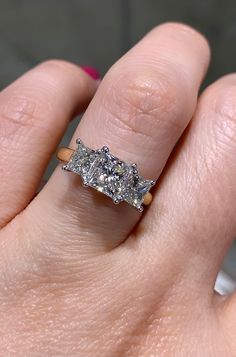 a woman's hand holding an engagement ring with three stones on top of it