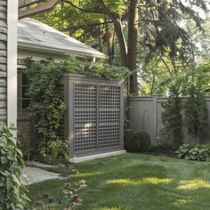 an outdoor garden with green grass and trees in the back yard, next to a house